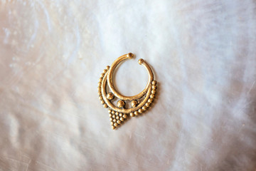 Brass metal nose decorative septum oriental boho jewelry on natural white shell background © marbenzu