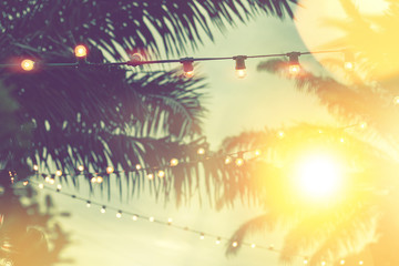 blurred light bokeh with coconut palm tree background on sunset, yellow string lights with bokeh...