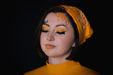 Girl with honey dripping down her face, creating a summer and bee inspired makeup look.