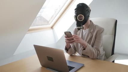 woman in suit, gas mask on head remotely works at home during quarantine of coronavirus pandemic COVID-2019, uses smartphone and laptop. Remote job, distant working online. Stay home funny concept - Powered by Adobe