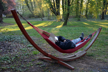 man sleeping in a rocking chair or hammock with a coronavirus face mask. he rests alone in nature where he cannot get infected by this terrible flu at all