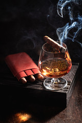 Smoking cigar and whisky on old humidor