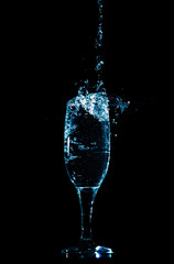 Splashes and drops of water in a glass are isolated on a black background.