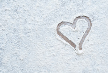 Culinary background. A heart is drawn with a finger on white flour. Copy space.