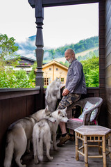 Old man plays with his dog Siberian Husky. Lifestyle. Active recreation. Alpine landscape.