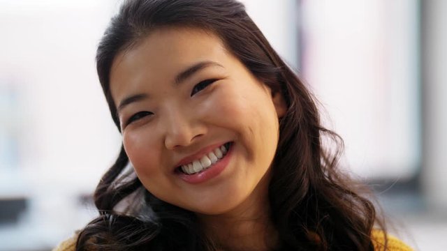 people, ethnicity and race concept - portrait of happy smiling asian young woman at home