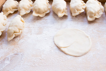 Fototapeta na wymiar National Russian cuisine. Pierogi or pyrohy, vareniki, served with cottage cheese and potatoes on board. Raw dumplings made of dough in handmade flour