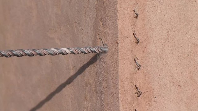 Close up video shot of worker drilling hole with perforator in concrete wall of cement building.