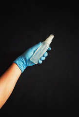 Fototapeta na wymiar hand in a blue sterile rubber glove and a bottle of antiseptic