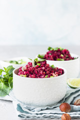 White ceramic bowls with buckwheat, beetroot, nuts and herbs warm salad, light grey concrete background. Dietary balanced food concept. Vegetarian and vegan meal. 