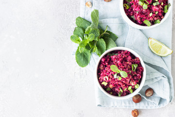 White ceramic bowls with buckwheat, beetroot, nuts and herbs warm salad, light grey concrete background. Dietary balanced food concept. Vegetarian and vegan meal. Top view.