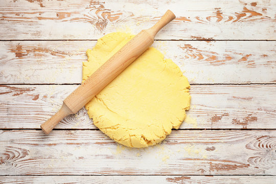 Fresh dough and rolling pin on wooden background