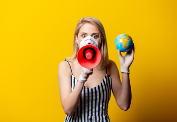 Obraz premium Blonde woman in face mask and gloves holds Earth globe and megaphone