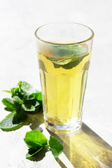 A tall glass of hot moorish mint tea in the morning light, sunlight shadow. Trendy style with artistic shadows.
