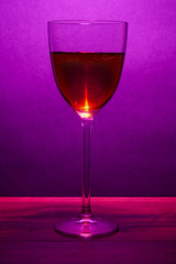 Glass of fortified red wine purple color background.