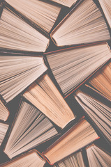 Many old multi-colored open books stand on the bookshelf in the library