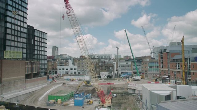 Timelapse of a skyscraper construction site with cranes, sun and clouds passing over building work in urban setting