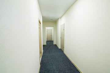 Long bright corridor with doors in a new hotel, hostel