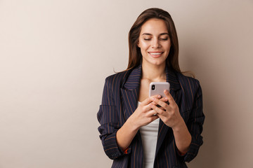Photo of cheerful businesswoman smiling and using cellphone