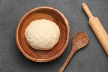 Fresh dough with utensils on dark background