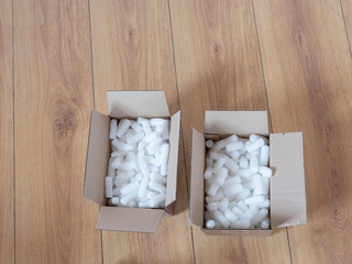 Two cardboard boxes with packing foam pellets top view, on wooden floor