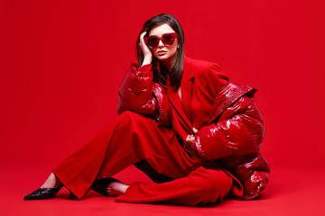 Fashion model in red suit, down jacket and sunglasses.