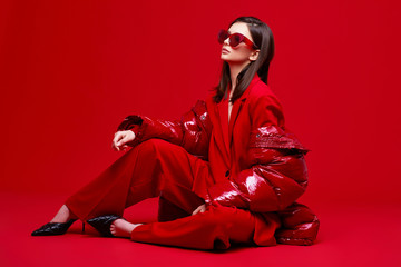 Fashion model in red suit, down jacket and sunglasses.