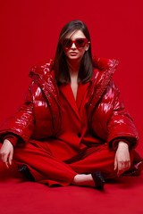 Fashion model in red suit, down jacket and sunglasses.