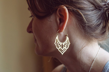 Woman wearing brass earrings in the shape of oriental lotus