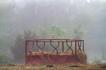 Cattle bale feeder with low hay on a farm, no animals. Agriculture industry facing hard times...