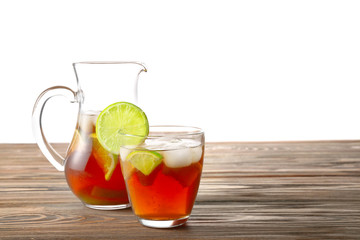 Glass and jug of tasty cold ice tea on table against white background
