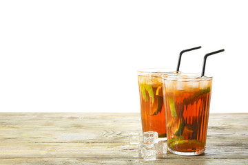 Glasses of tasty cold ice tea on table against white background