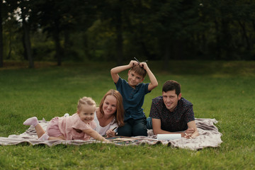 Happy young couple spending time with their daughter and son outdoors in the nature. Weekend activities concept