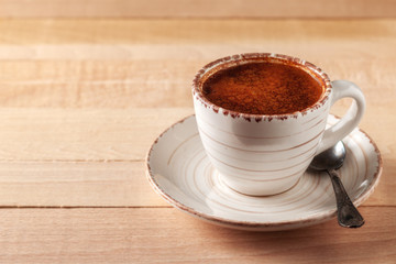 Coffee cup and saucer on a wooden table. Light background