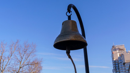 Obraz premium Old skool bronze fire bell on the classic blue sky background. Alarm fire concept.