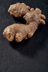 The root of ginger lies on a stone rectangular plate. vertical photo. top view. immunity against viruses.