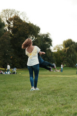 Lovely young mother playing with her preschool on the grass in the park, they are making roundabouts