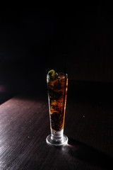 alcoholic cocktail on a neutral black background refreshing with coca cola and a slice of lime