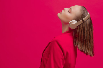 Cool young girl enjoys music in wireless headphones with a good mood. Bright colorful music poster. Wireless technology.