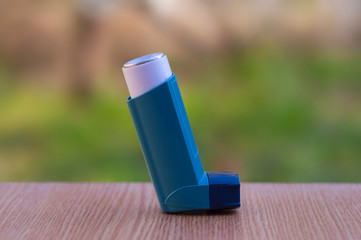 Asthma inhaler against the background of a blurry blooming Apple tree