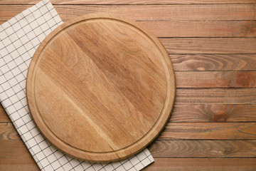 Fototapeta na wymiar Clean napkin with cutting board on wooden background
