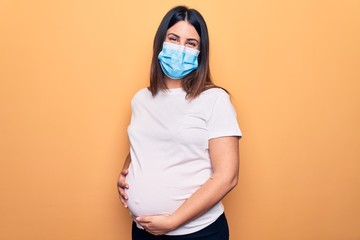 Young pregnant woman mother to be wearing protection mask for coronavirus disease with a happy and...