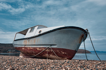 Abandoned old rusty boat on the sea shore with beautiful sky. Low wide angle view. Nature seascape