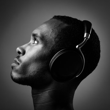 Side View Of Young Man Listening Music With Headphones Over Black Background
