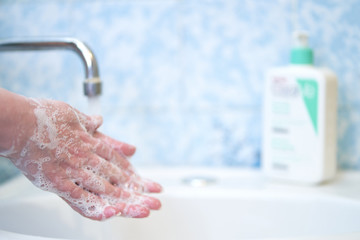 A woman uses soap and washes her hands under a faucet. Hygiene concept hand close-up.