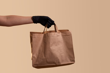 safe delivery for quarantine female hand in black latex glove gives paper bag