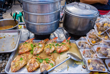 fish cooked on the stall of an alley kitchen cart in Bangkok, Thailand