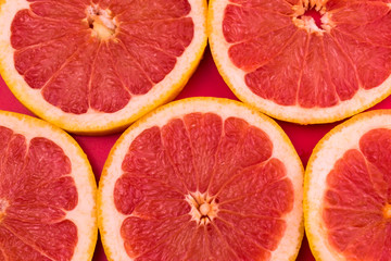 
Background of red grapefruit slices on a red background.