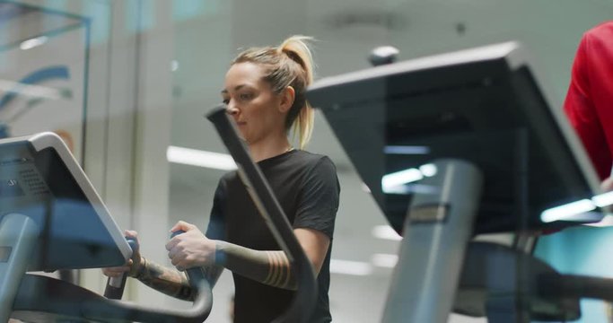 woman exercising with elliptical walking machine at gym.Front view, slow motion. Woman training at walking machine. Woman walking on gym machine