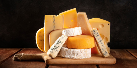 Cheese panorama, many different types of cheeses, a side view on a dark background